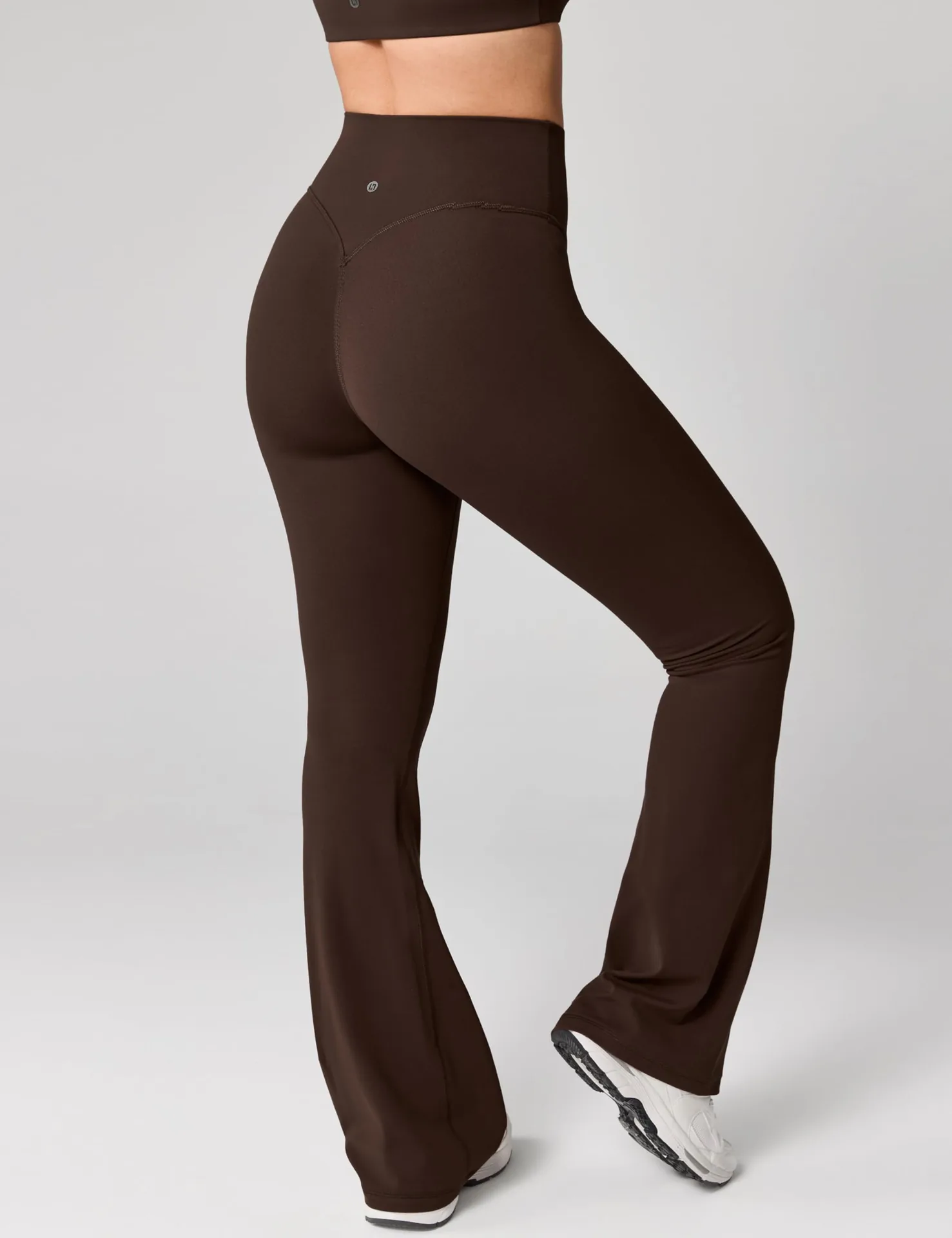 Back view of brown UNISSU flare leggings with white sneakers