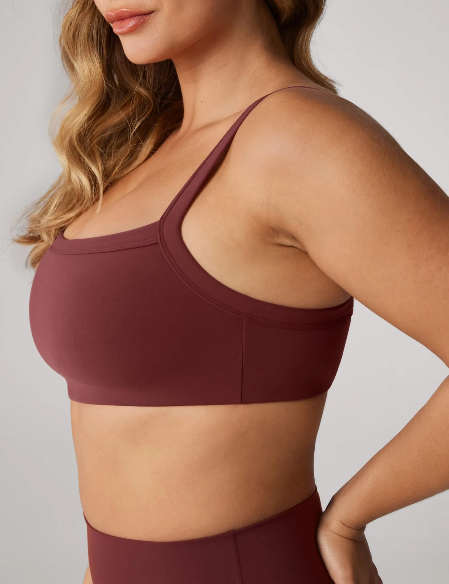 Smiling woman in a burgundy UNISSU sports bra with a square neckline