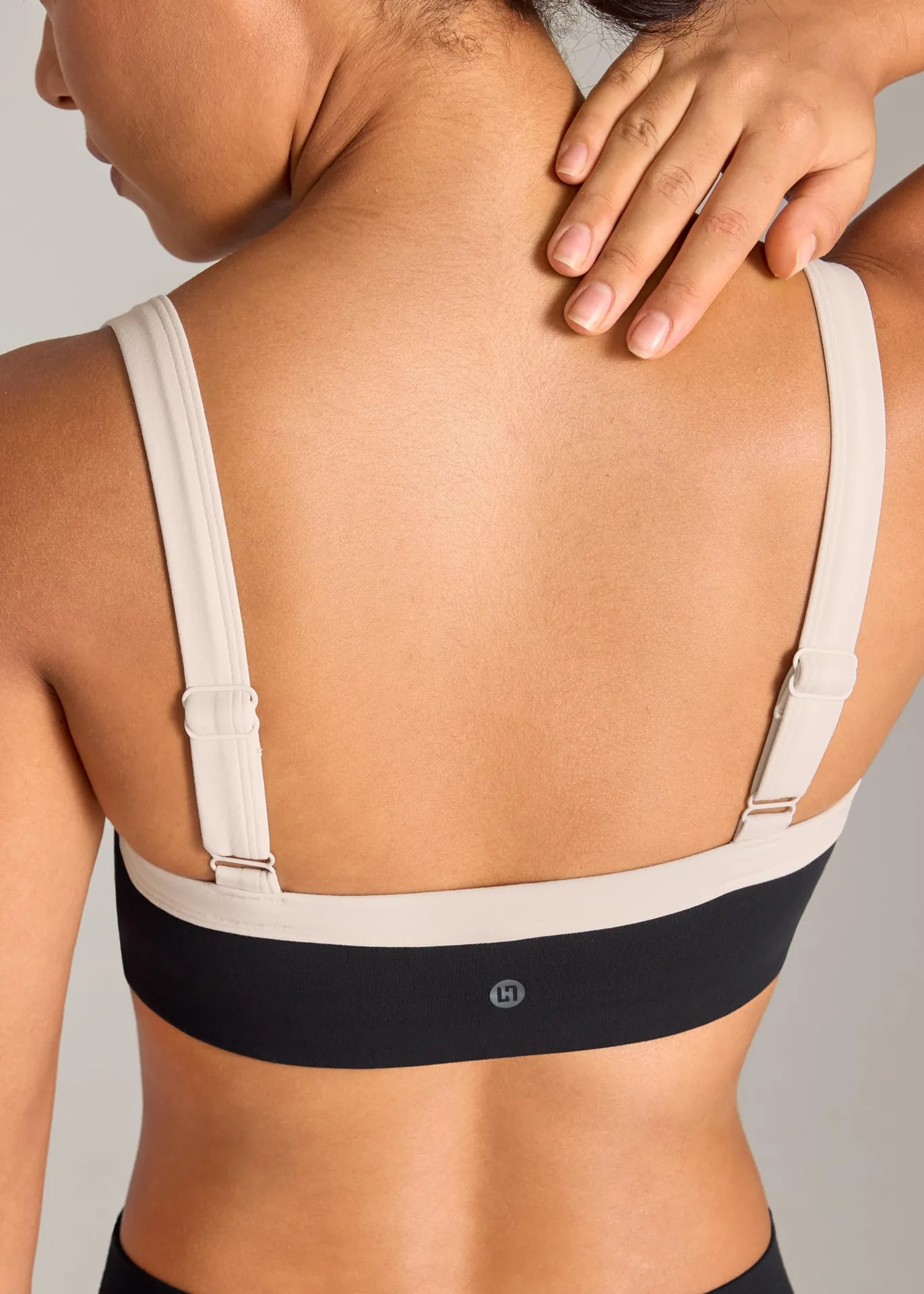 Back of a two-tone UNISSU sports bra with adjustable straps