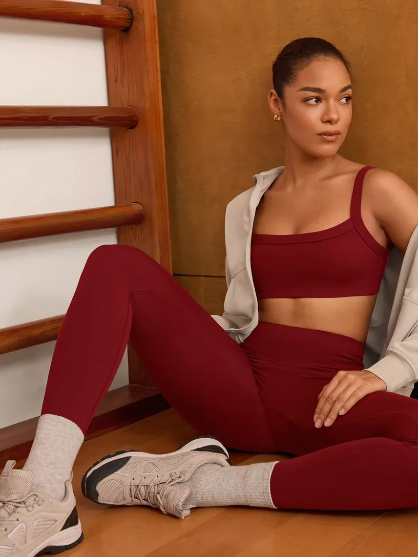 Woman sitting on a gym floor in a red UNISSU sports bra and leggings